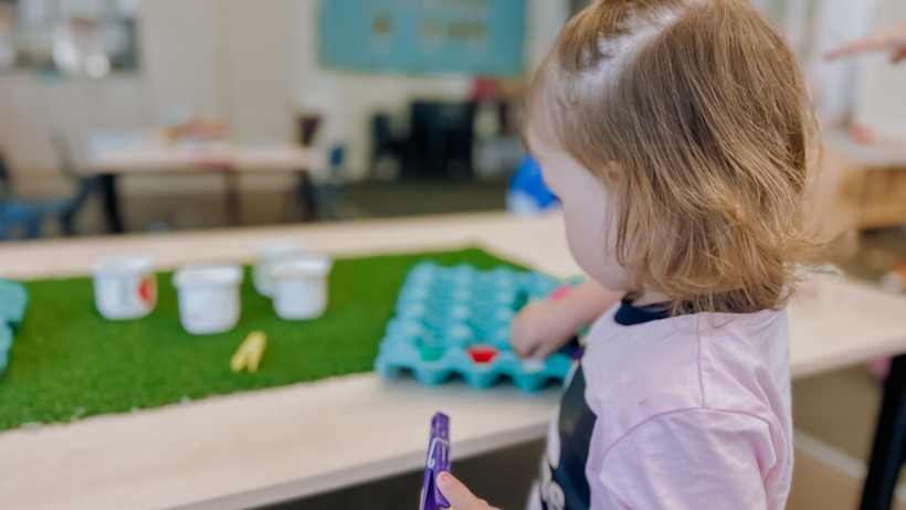 Child developing fine motor skills playing with a peg at Active Explorers preschool central city Christchurch