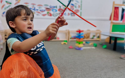 Child playing with a straw creation made at Active Explorers preschool in Christchurch