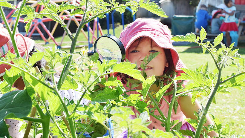 girl with magnifying glass at daycare