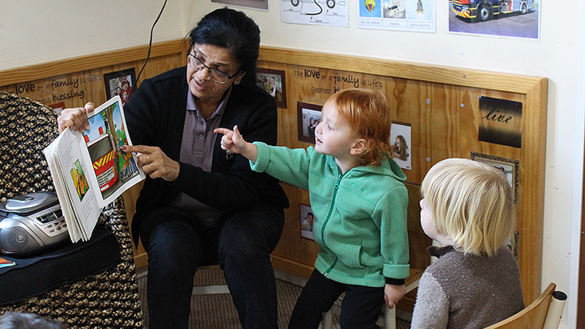 teacher reading a book to children at daycare