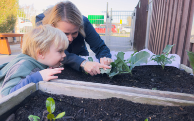 A young child and a teacher exploring the gardens and natural environments at Active Explorers preschool in Rolleston